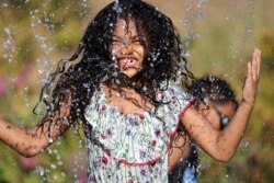 Isis Macadaeg (7 tahun) bermain air di Jefferson Park, saat gelombang panas melanda kawasan Seattle, Washington, AS, 27 Juni 2021. (REUTERS/Karen Ducey)