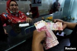 A customer holds Indonesian rupiah bank notes at a money changer in Jakarta, Indonesia, Aug. 13, 2018.