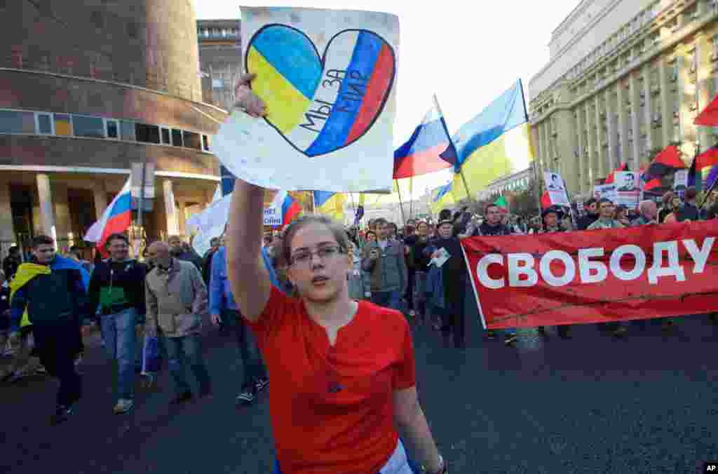 A girl carries a banner reading "we're for peace" during an anti-war rally in downtown Moscow, Russia, Sept. 21, 2014. 