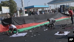 Những người Afghanistan thu lượm những gì còn xót lại sau một đánh bom chết người xảy ra tại một cuộc biểu tình của sắc dân Hazaras, ở Kabul, Afghanistan, thứ bảy ngày 23 tháng 7 năm 2016.