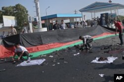 Afghans gather property, left behind by victims of a deadly explosion that struck a protest march by ethnic Hazaras, in Kabul, Afghanistan, Saturday, July 23, 2016.