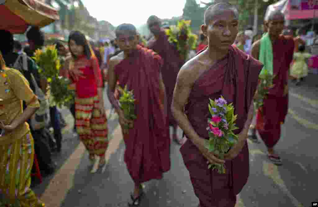 Buddhist monks and devotees carry flowers to offer at Shwedagon pagoda in Rangoon, Burma, April 17, 2014. 