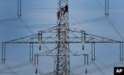 FILE - In this April 11, 2011 file photo, workers of the German energy company RWE prepare power supply on a high power pylon in Moers, Germany. The world's facing an energy crunch. (AP Photo)