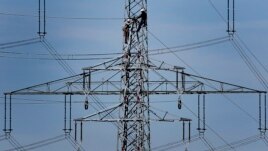 FILE - In this April 11, 2011 file photo, workers of the German energy company RWE prepare power supply on a high power pylon in Moers, Germany. The world's facing an energy crunch. (AP Photo)