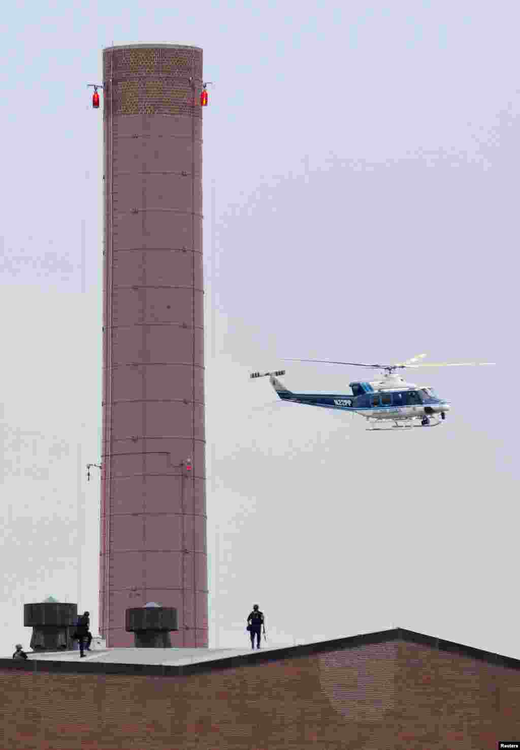 Trực thăng và cảnh sát tuần tra trên mái một tòa nhà sau khi vụ nổ súng xảy ra tại Công xưởng Hải quân ở thủ đô Washington, ngày 16 tháng 9, 2013.