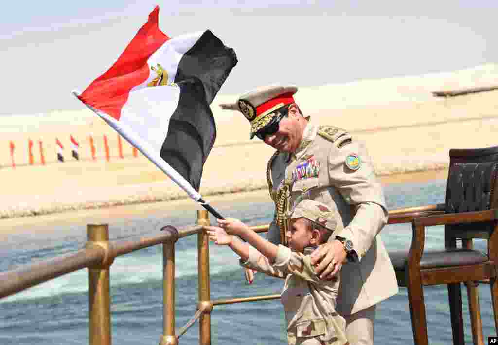 In this picture provided by the office of the Egyptian Presidency, President el-Sissi smiles at a boy as he waves the national flag from a monarchy-era yacht that sailed to the venue of a ceremony for extension of the Suez Canal, 6 Aug. 2015.