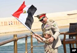 FILE - In this picture provided by the office of the Egyptian Presidency, Egyptian President Abdel-Fattah el-Sissi smiles at a boy dressed in a tiny military uniform as he waves the national flag from a monarchy-era yacht that sailed to the venue of a ceremony unveiling a major extension of the Suez Canal in Ismailia, Egypt, Thursday, Aug. 6, 2015.