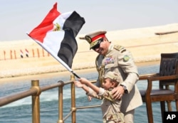 FILE - In this picture provided by the office of the Egyptian Presidency, Egyptian President Abdel-Fattah el-Sissi smiles at a boy dressed in a tiny military uniform as he waves the national flag from a monarchy-era yacht that sailed to the venue of a ceremony unveiling a major extension of the Suez Canal in Ismailia, Egypt, Thursday, Aug. 6, 2015.