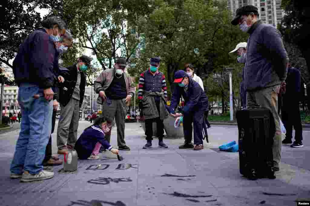 A girl practices calligraphy of Chinese characters on a street at a park following the outbreak of coronavirus disease (COVID-19), in downtown Shanghai, China.