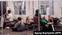 Pasien dirawat di bawah tenda darurat yang didirikan di kompleks rumah sakit untuk menangani masuknya orang yang menderita virus corona, di Yogyakarta pada 13 Juli 2021. (Foto: AFP/Agung Supriyanto)