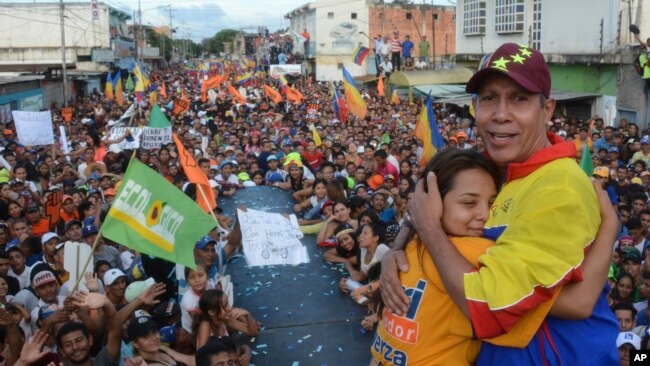 El candidato presidencial opositor venezolano Henri Falcon, (derecha) abraza a una partidaria durante su acto de cierre de campaña el jueves, 17 de mayo, de 2018, en Barquisimeto, Venezuela.