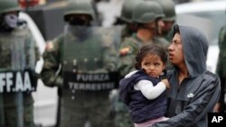 Un hombre que carga a una niña sale de un camino después de que soldados llegaran a reabrirlo en Quito, Ecuador, el lunes 7 de octubre de 2019. (AP Foto/Dolores Ochoa)