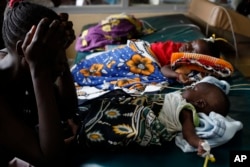 An unidetified mother as watches over her child who is suffering from severe malaria, as other children lay nearby, in the Siaya hospital in Western Kenya. Photo taken on Oct. 30, 2009.