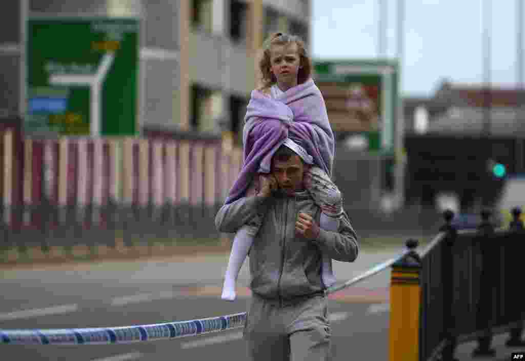 Seorang pria menggendong anak perempuannya di atas punggung di dekat stasiun Victoria di kota Manchester, Inggris, yang baru sehari sebelumnya dilanda serangan teroris.