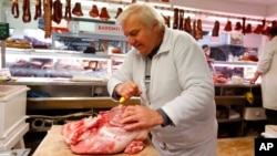 FILE - Vendor Misi Kovacs prepares meat to sell at a market in Budapest, Hungary, Nov. 20, 2021. Around the world, rising consumer prices fueled by high energy costs and supply chain disruptions are putting a pinch on households and businesses.