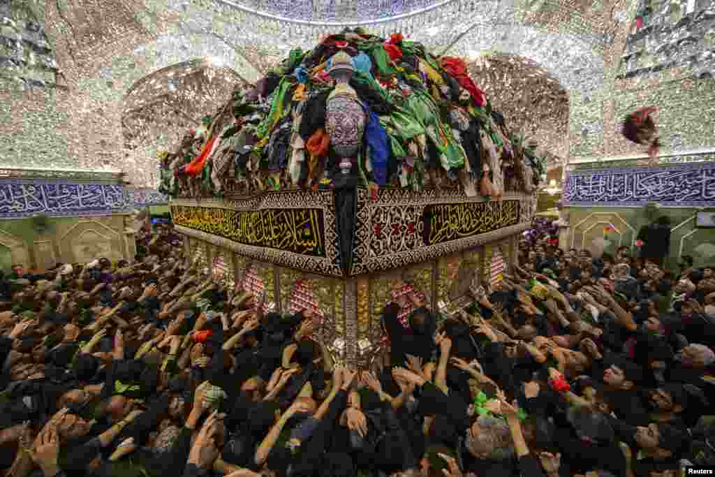 Muslim Syiah berusaha menyentuh makam Imam al-Abbas yang terletak di dalam tempat pemujaan Imam al-Abbas shrine menandai Arbain di kota suci Karbala, barat daya Baghdad, 13 Desember 2014.