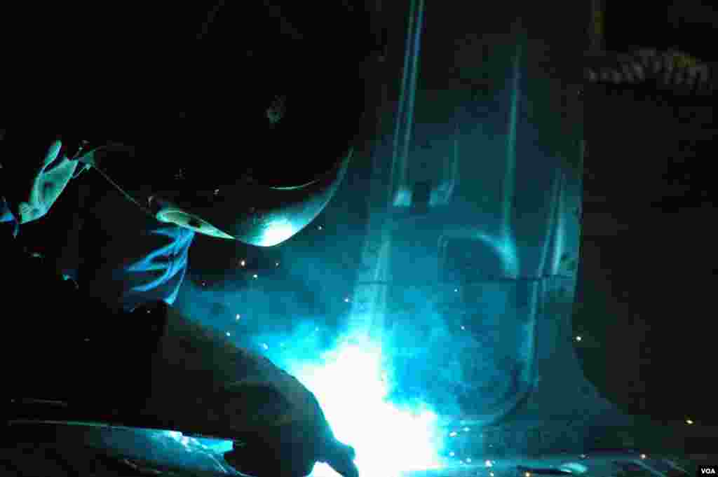 A worker welding inside the body of a car on a GM assembly line in Thailand. (Steve L. Herman/VOA)