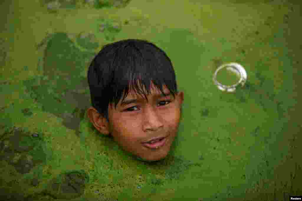 Seorang anak laki-laki berenang di sebuah kolam yang tertutup oleh ganggang di kota Bhaktapur, Nepal.