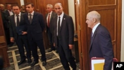 Aides and security officers watch as Greek Prime Minister George Papandreou arrives at an urgent cabinet meeting in the Greek parliament in Athens, Greece, November 3, 2011.
