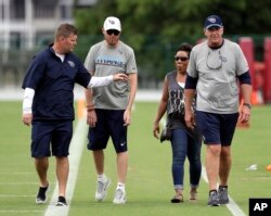 FILE - Former Tennessee Titans linebacker Tim Shaw, second from left, leaves the field with Titans general manager Jon Robinson, left, and head coach Mike Mularkey, right, after a team activity at its training facility in Nashville, Tenn., June 15, 2017. Shaw, who was diagnosed with ALS in 2014, has worked with the special teams staff and players.