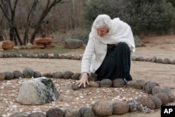 FILE - In this Jan. 27, 2010 photo, Angel Valley Retreat Center owner Amayra Hamilton pauses at a memorial marking the site where three people died during a sweat lodge ceremony in October 2009 in Sedona, Ariz.