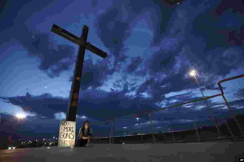 Una mujer se sienta al lado de un cartel con un mensaje que dice: &quot;&iexcl;No más armas! Hagan el Amor&uml;, en Juárez, México, el sábado 3 de agosto de 2019, mientras las personas se reunían para una vigilia por los 3 ciudadanos mexicanos que fueron asesinados en un tiroteo en un centro comercial de El Paso.&nbsp;(AP Photo/Christian Chavez).