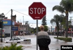 A resident watches as floodwaters enter the main street of Lismore, Australia, March 31, 2017, after heavy rains associated with Cyclone Debbie swelled rivers to record heights across the region.