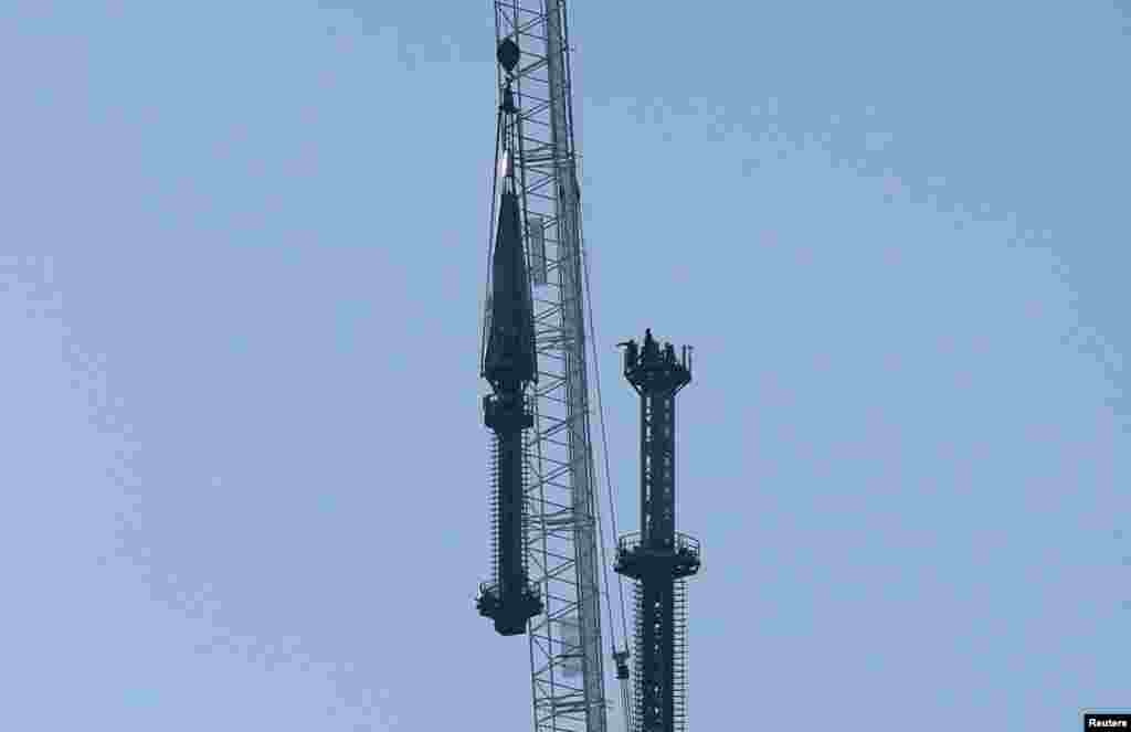 Iron workers wait for the final piece of the One World Trade Center spire to be brought to them for attachment to the building, in New York, May 10, 2013.