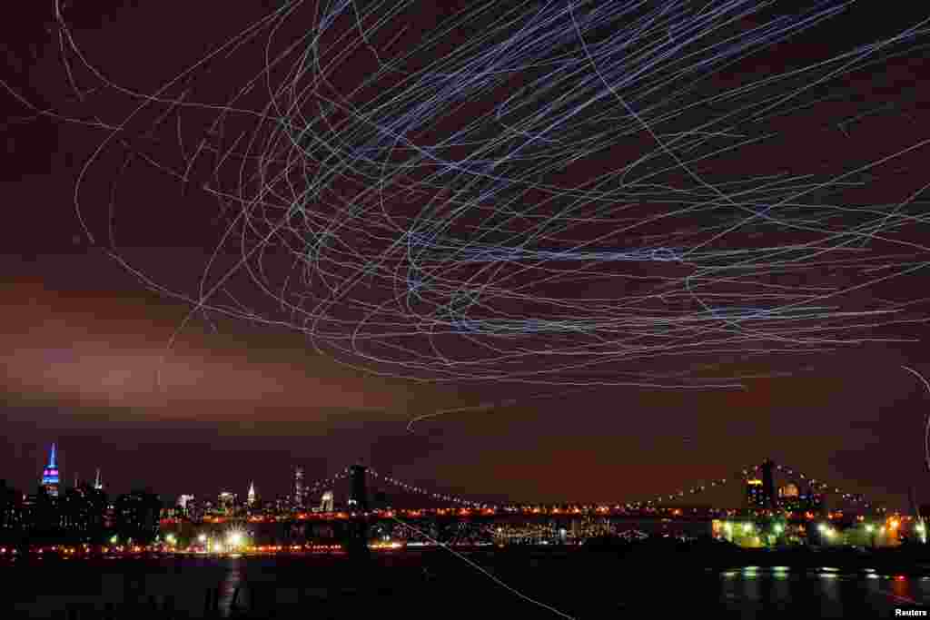 LED lights attached to pigeons leave light trails in the sky while they fly as part of the &quot;Fly By Night&quot; art installation by Duke Riley above the Brooklyn borough of New York, May 5, 2016.