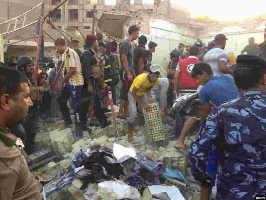 Iraqi security forces and people gather at the site of a car bomb attack in Kut, Iraq, July 14, 2013. 