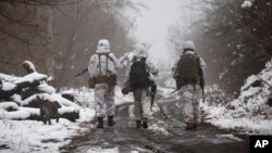 FILE - Ukrainian soldiers walks near the line of separation from Russia-backed rebels near Katerynivka, Donetsk region, Ukraine, Dec 7, 2021.