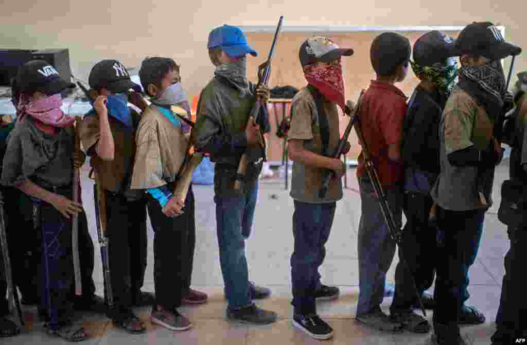 Children holding toy weapons and wooden sticks, take part in a training demonstration of the Regional Coordinator of Community Authorities (CRAC-PF) vigilante force, in the village of Ayahualtempa, Guerrero State, Mexico.