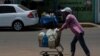 Una mujer empuja un carrito cargado con botellas de agua recolectadas de un grifo improvisado en una calle de Maracaibo, Venezuela, el 25 de mayo de 2020, durante la pandemia del coronavirus COVID-19.