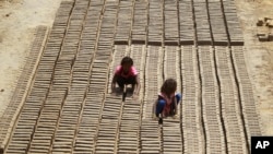FILE - Indian children work at a brick factory on the outskirts of Jammu, India, May 1, 2018. 