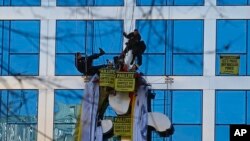 French police officers, on top, arrive to arrest members of the group Greenpeace hanging with a banner on the building of the energy giant EDF during a nuclear protest in Paris, Dec. 14, 2016. 
