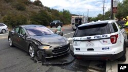 Sedan Tesla, kiri, dalam mode autopilot yang menabrak mobil polisi yang sedang diparkir, di Laguna Beach, California, 29 Mei 2018. (Foto: AP)