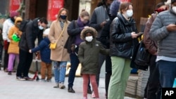 FILE - People wait in line outside a COVID-19 walk-in testing site, Dec. 5, 2021, in Cambridge, Mass.