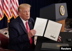 U.S. President Donald Trump shows signed executive orders for economic relief during a news conference amid the spread of the coronavirus disease (COVID-19), at his golf resort in Bedminster, New Jersey, Aug. 8, 2020.