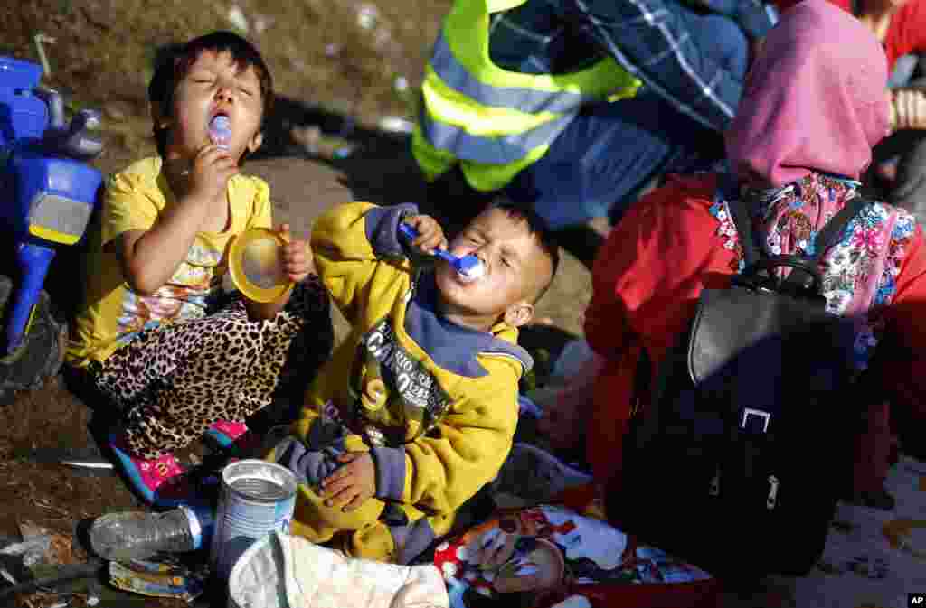 Young children eat milk powder as they wait for a bus in a temporary holding center for migrants near the border between Serbia and Hungary in Roszke, southern Hungary.