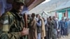 A member of the Indian Border Security Force stands guard as people wait to vote at a polling station during the third and final phase of the assembly election, in north Kashmir's Bandipora district, Oct.1, 2024.