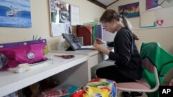 FILE - A student takes a class online at her home in San Francisco, March 19, 2020. Hundreds of students in Sioux Falls, South Dakota, did not take part in online learning when schools closed, one report shows.