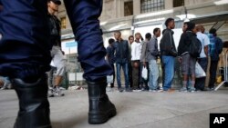 Des migrants font la queue pour être enregistrés par des bénévoles de Progetto Arca avant d’être conduits à un centre à Milan, en Italie, le dimanche 14 juin 2015.