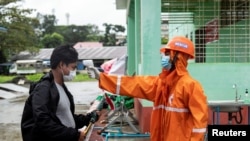 A volunteer checks the temperature of a man at the entrance of Sittwe Hospital, amid the outbreak of the coronavirus disease (COVID-19), in Sittwe, Rakhine State, Myanmar August 24, 2020. REUTERS/Stringer NO RESALES NO ARCHIVES