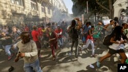 Protesting university students flee as police fire stun grenades outside Parliament in Cape Town, South Africa, Oct. 21, 2015.