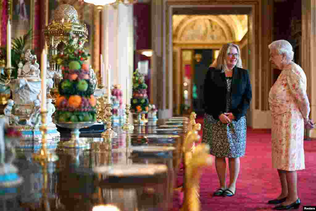 ملکہ برطانیہ ایک خاتون عملے سے ڈائننگ ٹیبل اور ہال سے متعلق معلومات پر تبادلہ خیال کرتے ہوئے۔