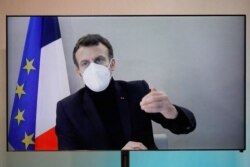 FILE - French President Emmanuel Macron, who tested positive for the coronavirus, is seen on a screen as he attends a video conference in Paris, France, Dec. 17, 2020.