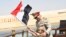 In this picture provided by the office of the Egyptian Presidency, President el-Sissi smiles at a boy dressed in a tiny military uniform as he waves the national flag from a monarchy-era yacht that sailed to the venue of a ceremony for extension of the Su