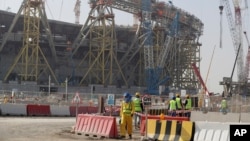 کارگران در پاییز ۱۳۹۸ در ورزشگاه «لوسیل»، یکی از ورزشگاه‌های اختصاص یافته به مسابقات جام جهانی قطر،‌ کار می‌کنند (آرشیو)