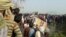In this image from video, people gather at the site where a truck loaded with sand collided with a school bus in the northern Indian state of Uttar Pradesh, Jan. 19, 2017.