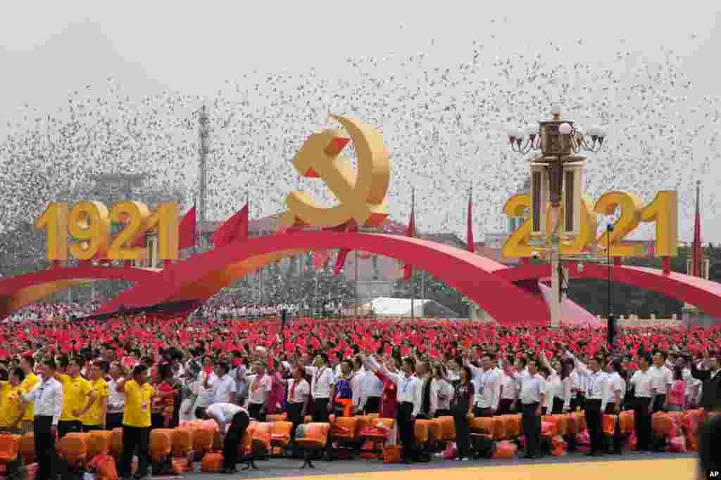 Attendees wave Chinese flags during a ceremony at Tiananmen Square to mark the 100th anniversary of the founding of the ruling Chinese Communist Party in Beijing.